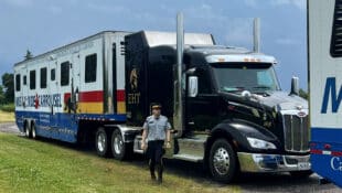 An RCMP officer standing outside a large horse van.