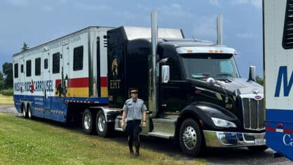 An RCMP officer standing outside a large horse van.