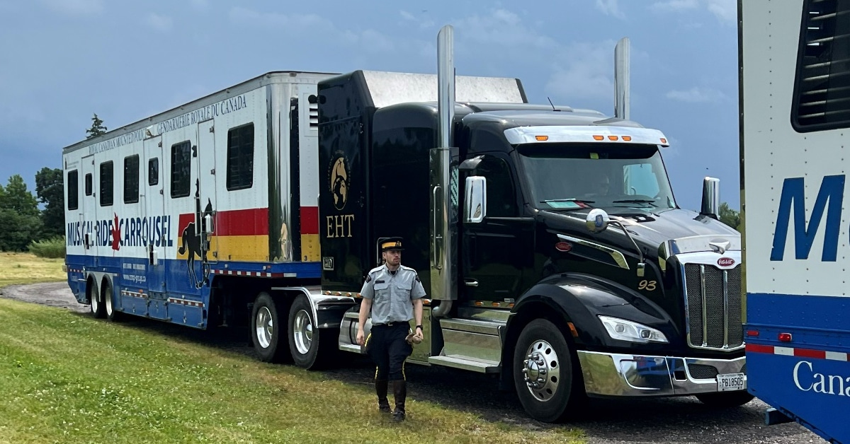 An RCMP officer standing outside a large horse van.