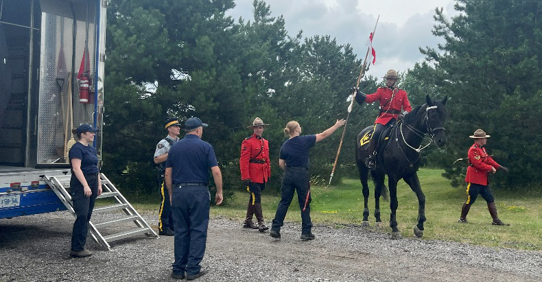 A woman handing a rider a lance.