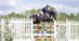 A man jumping a black horse over a fence in England.
