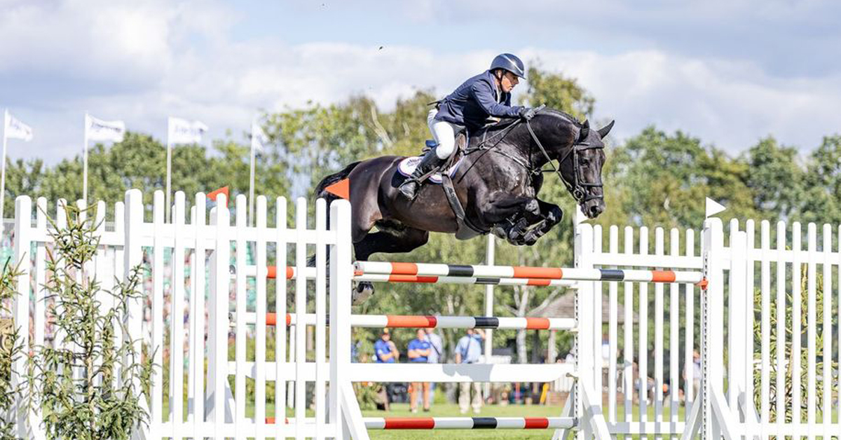 A man jumping a black horse over a fence in England.