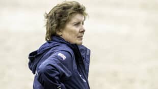 A woman standing in a jumping arena.