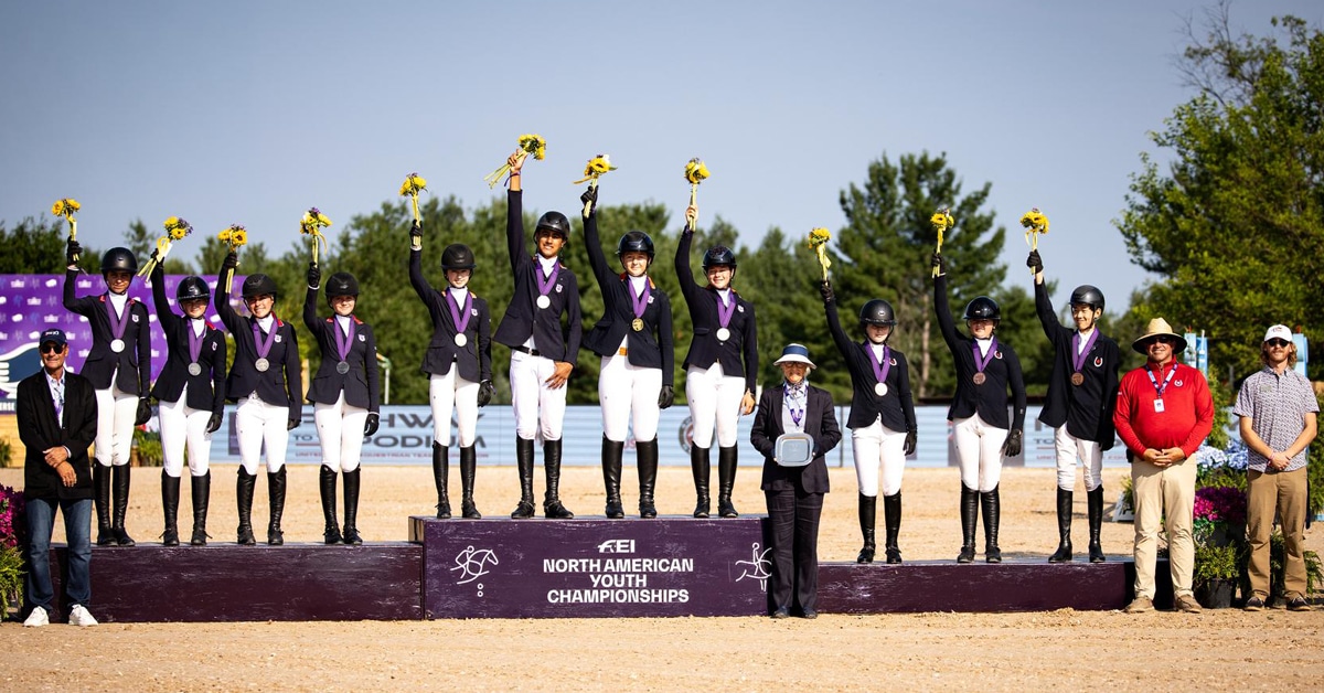 Three groups of riders on a podium waving flowers.