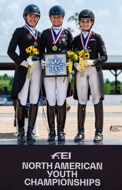 Three dressage riders standing on a podium.