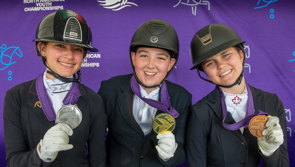 Three young ladies showing off their medals.