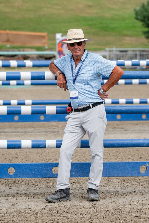 A man in a hat and a blue shirt leaning against a jump.