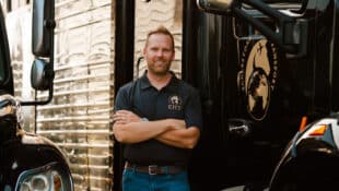 A man standing near two large horse vans.