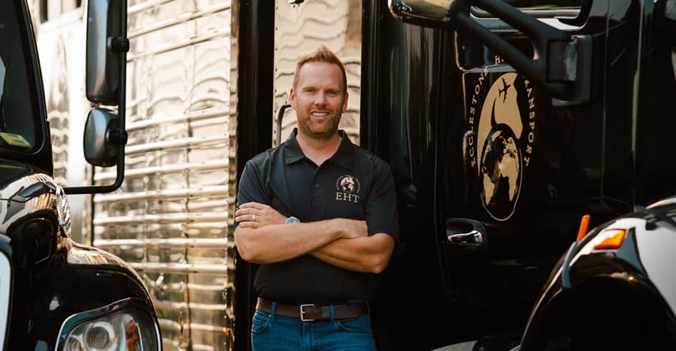 A man standing near two large horse vans.