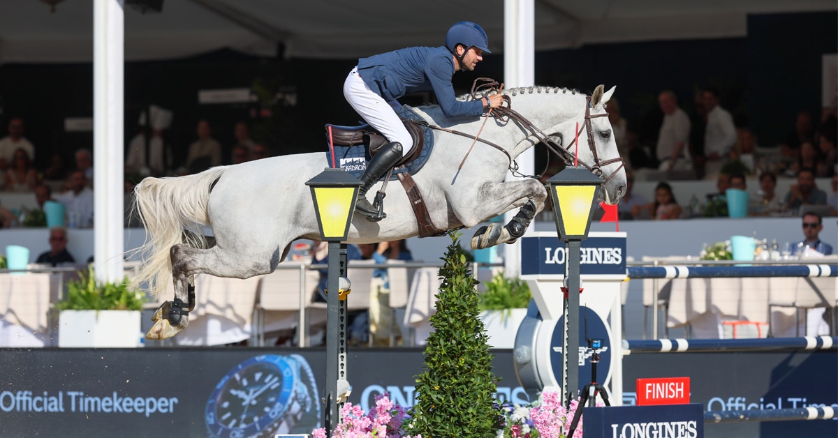 A man jumping a grey horse over a fence in London.