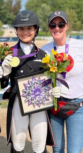Two smiling women, one holding up a medal.
