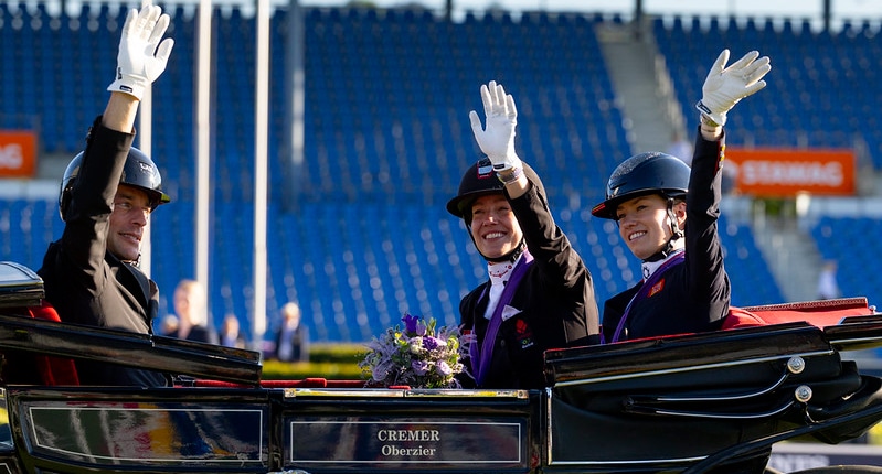 Three dressage riders in a carriage.