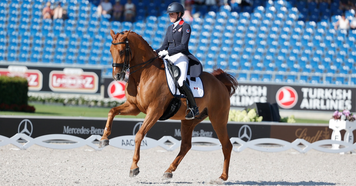 A woman riding a chestnut horse in a dressage arena.