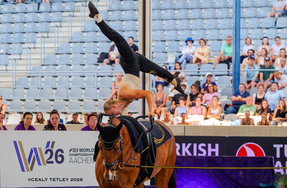 A woman performing a vaulting move on a horse.