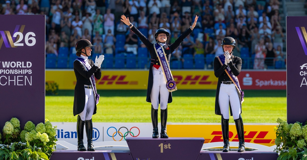 Three women waving from a podium.