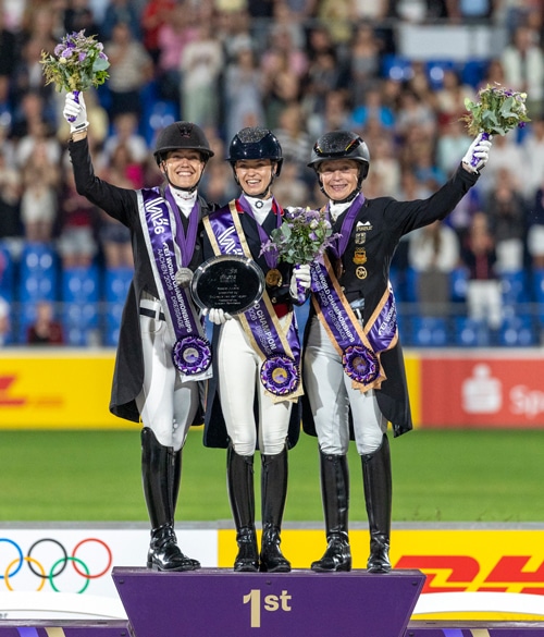 Three smiling women standing on a podium.