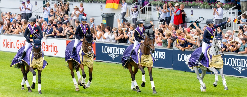 A team of four riders and horses during a victory gallop.