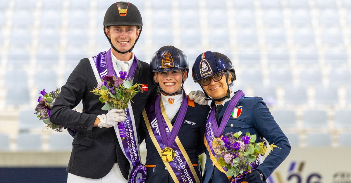 Three para riders on a podium, holding flowers.