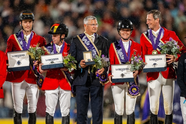 A show jumping team on a podium holding watch boxes.