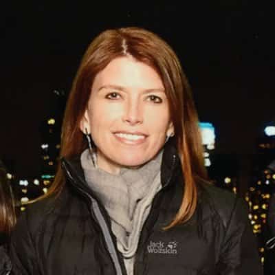 A smiling woman with a night city behind.