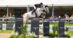 A man jumping a grey horse over a fence in the Hamptons.