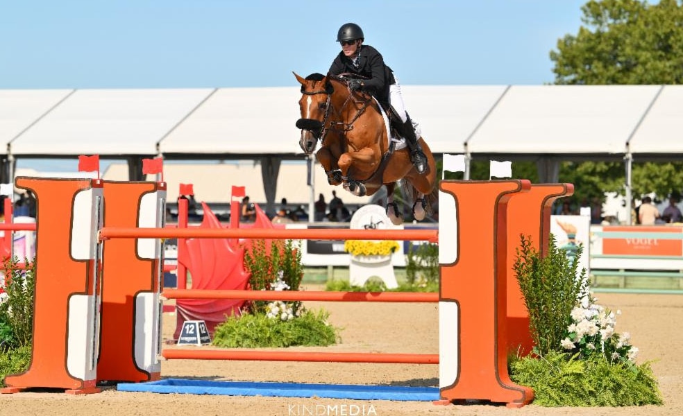 A man jumping a chestnut horse over a fence in the Hamptons.
