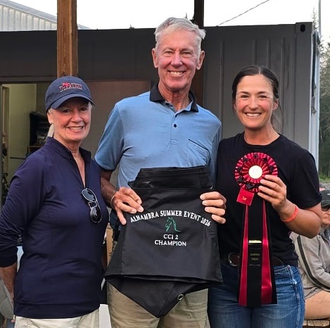 Two women and a man posing for a winner's photo.