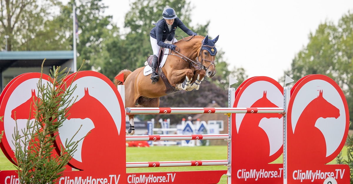 A woman jumping a chestnut horse over a fence in England.