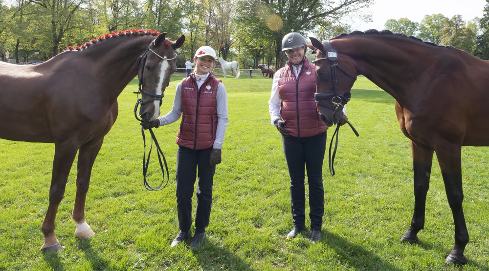 Two smiling Canadian women holding a pair of bay horses.