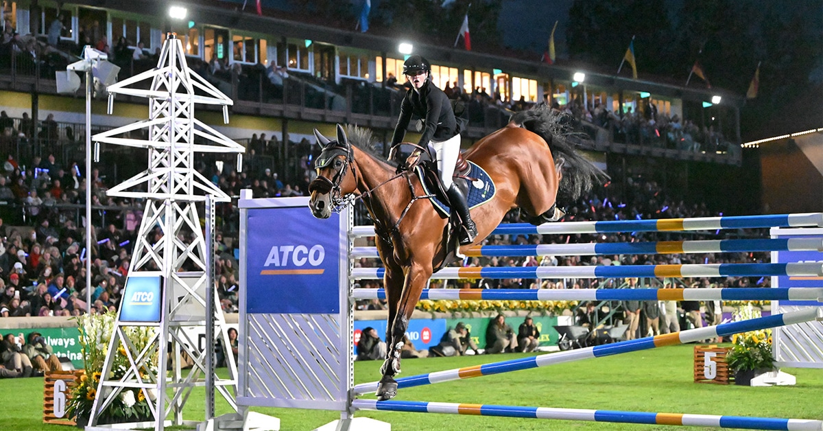 A woman jumping a bay horse over a six-bar jump at Spruce Meadows.