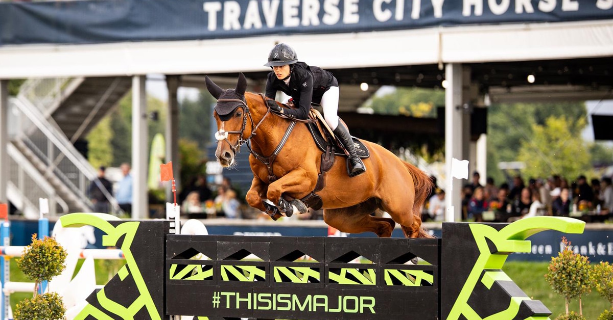 A woman jumping a chestnut mare over a fence at Traverse City.