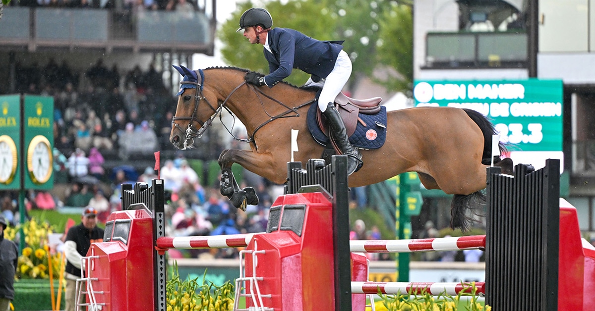 A man jumping a bay horse over a fence at Spruce Meadows.