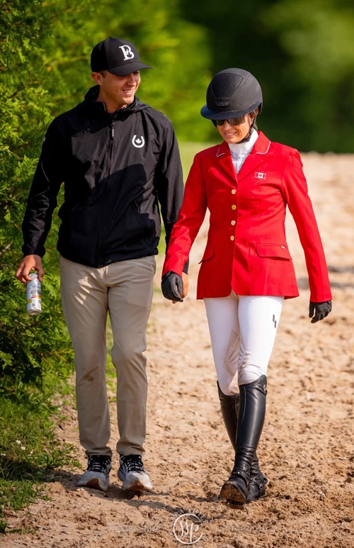 A man in a black jacket walking with a woman in a red jacket.