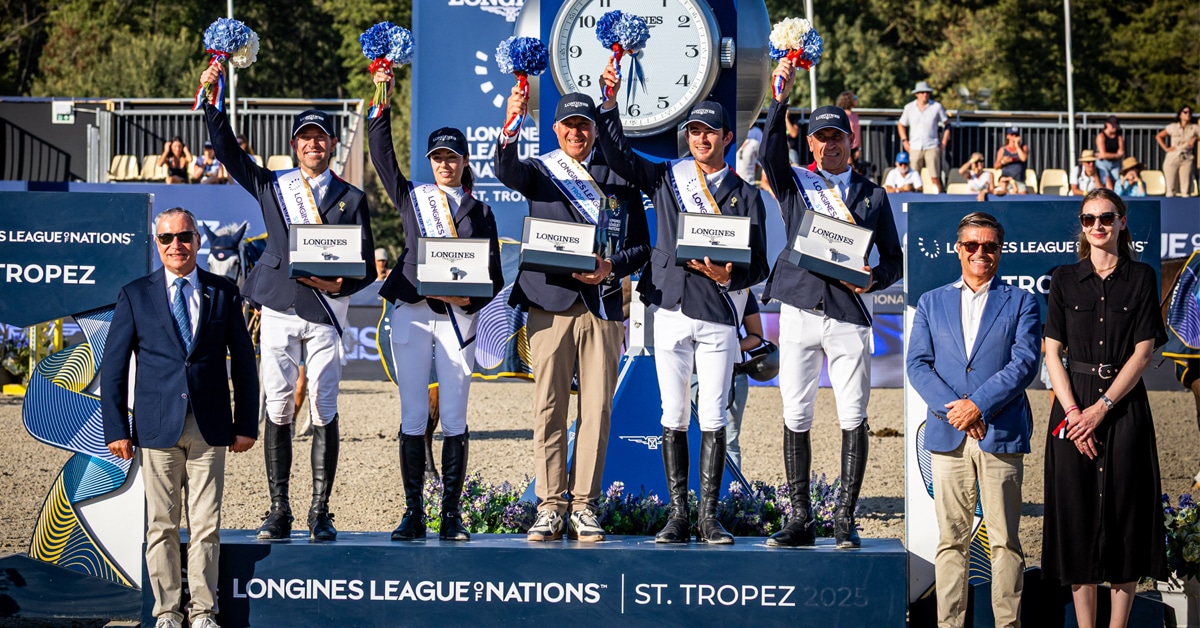 A team of riders and support staff on a podium in France.