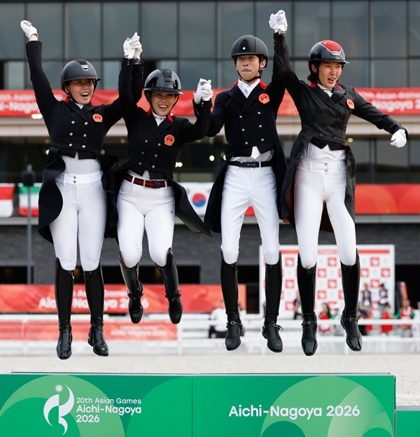 A team of four people leaping for joy on a podium.