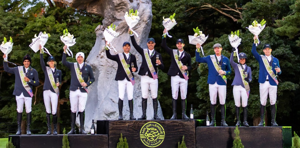 Three teams standing on a podium, waving.
