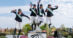 Four eventers leaping off a podium.