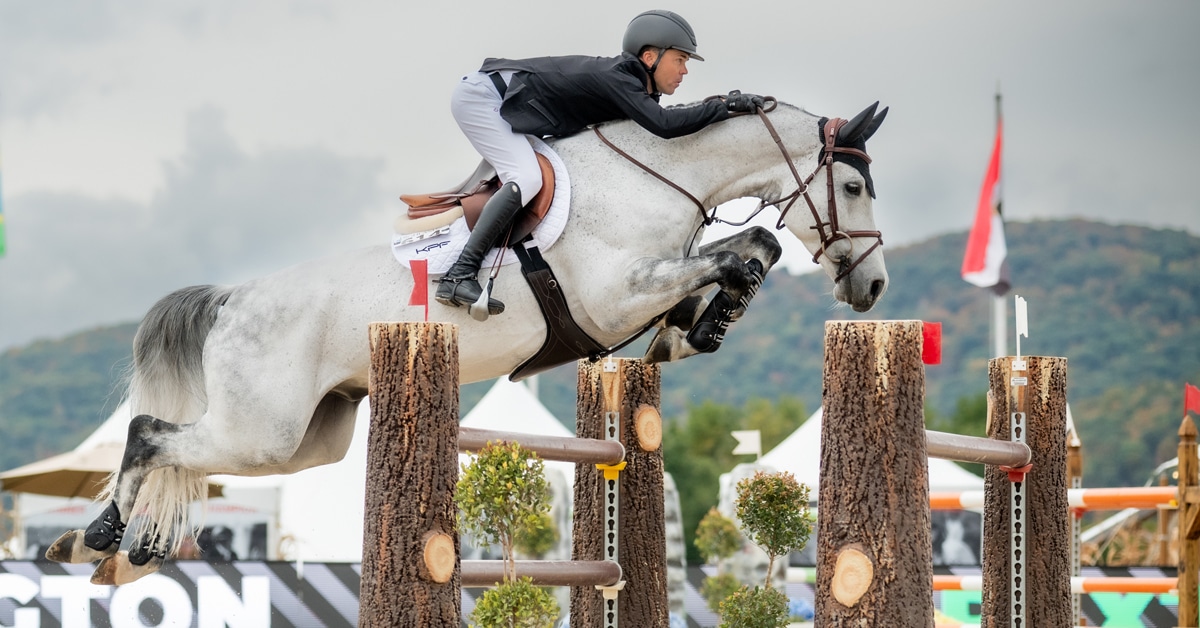 A man jumping a grey horse over a fence in the Hudson Valley.
