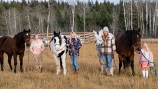 A family standing in a field with their horses.