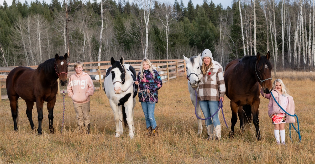 A family standing in a field with their horses.