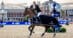A man on a bay horse, waving his hat during a victory gallop.
