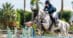 A woman jumping a grey horse over a fence in Spain.