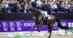 A woman riding a dark bay dressage horse during a test in Denmark.