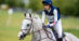 A young rider galloping a grey event horse.