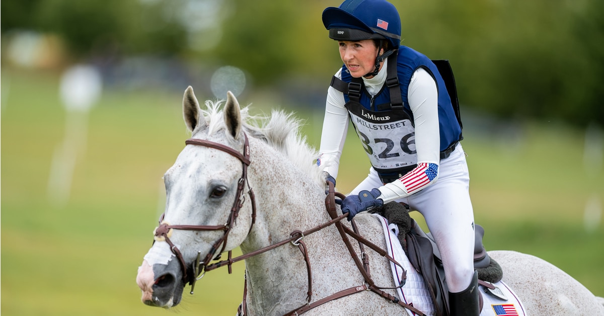 A young rider galloping a grey event horse.