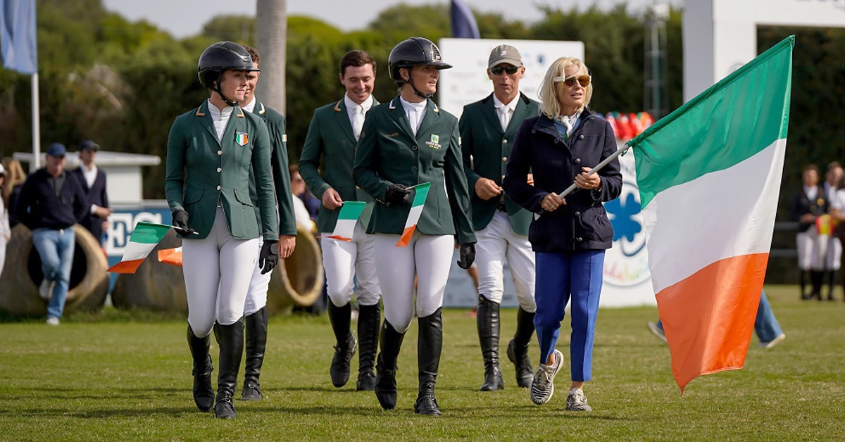 An Irish team walking with a flag at a horse show.